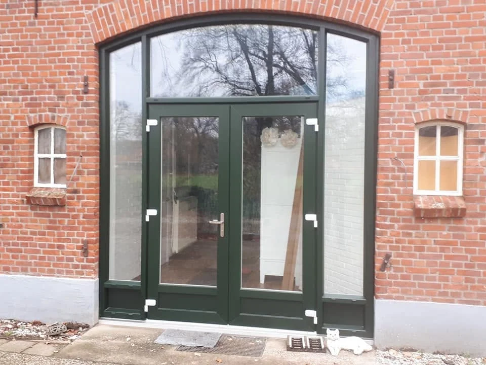 Groene pui met glas in boogvormige bakstenen gevel