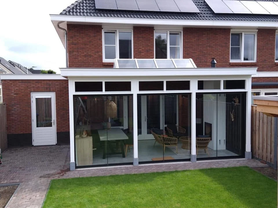 Serre met glazen schuifwand, daklicht en strak wit boeiboord